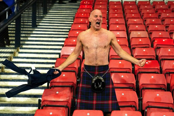 Ein Fan mit nacktem Oberkorper im Schottenrock schreit vor Freude auf der Stadiontribüne