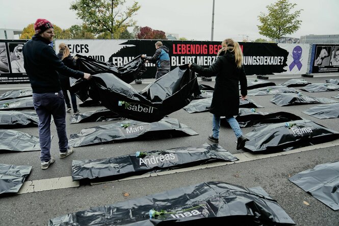 Menschen platzieren Leichensäcke auf einer Straße