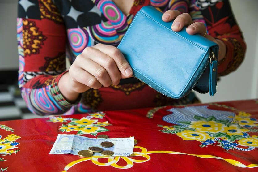 Eine Person leert ihr Portmonnaie auf einen Tisch