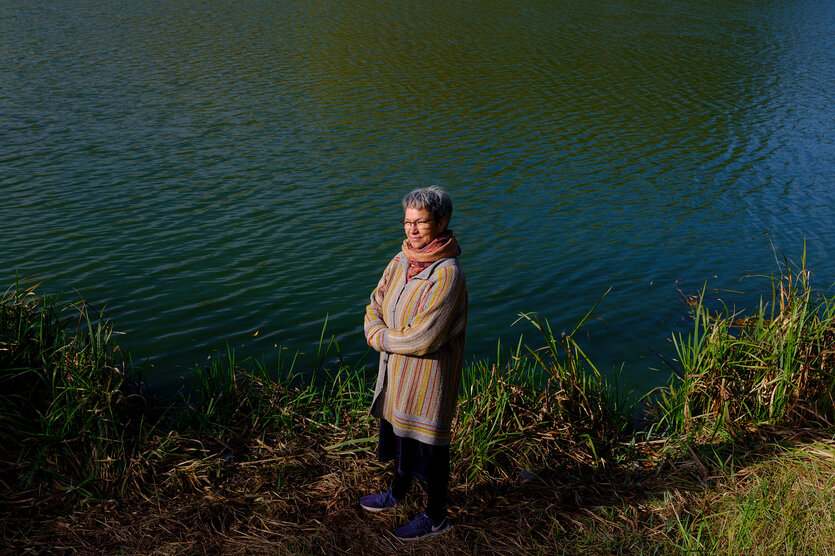 Eine Frau steht am Ufer eines Sees