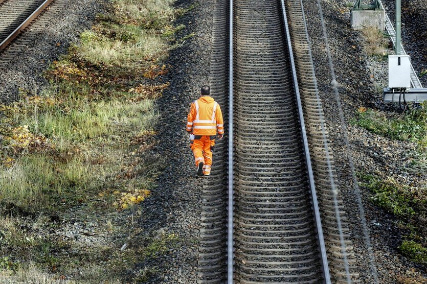 Ein Bauarbeiter läuft an Bahngleisen entlang