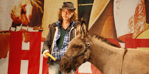 Der Musiker Helge Schneider posiert zusammen mit dem Esel Lilly waehrend eines Fototermins fuer die Fotografen. In seiner Hand hält er eine Karotte.