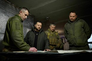 Präsident Selenskyj schaut mit Soldaten auf eine Karte.