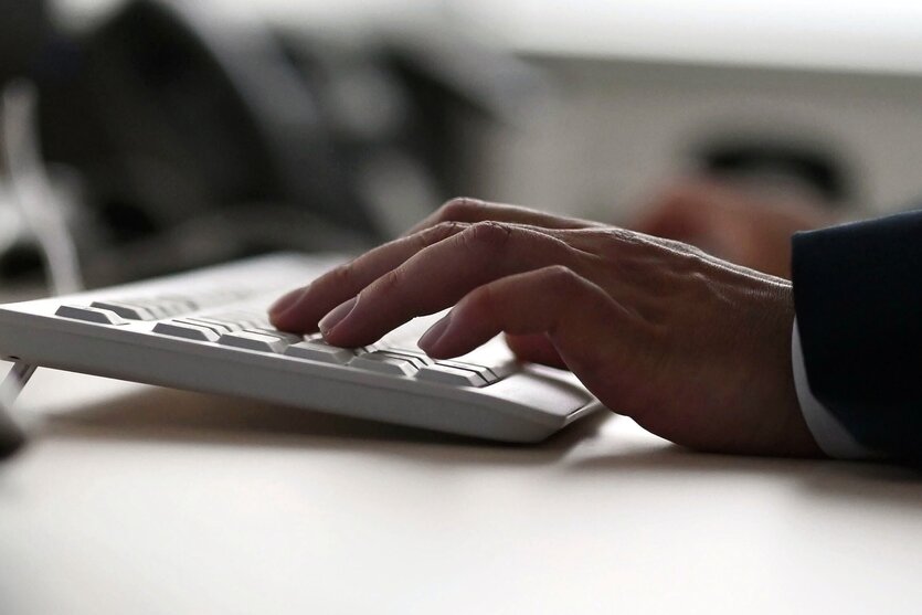 Männerhand auf der Tastatur eines Computers in einem Büro
