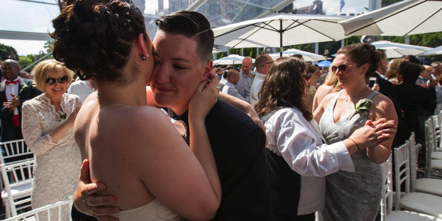 Zwei Frauen in Hochzeitskleidung umarmen sich