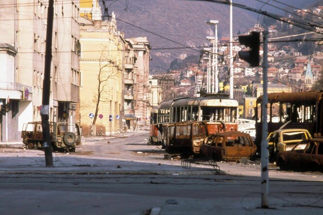 Straße mit zerstörten Straßenbahnwaggons und Autos in Sarajevo