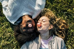 Zwei Personen liegen auf einer Wiese und machen Kaugummiblasen