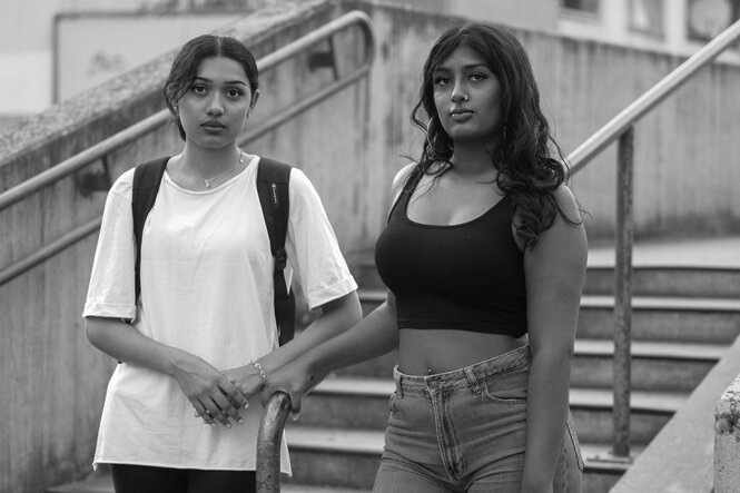 Zwei Personen stehen in einer Siedlung vor einem Wohnhaus.