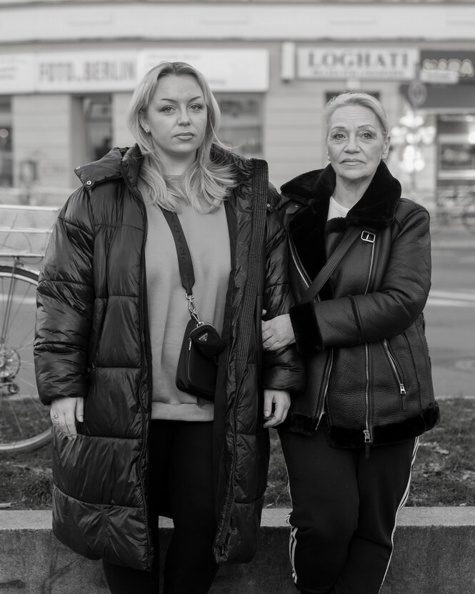 Zwei Personen vor Geschäften in einer Straße.