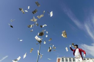 Ein Mann als Zauberer verkleidet schmeißt Geldscheine in die Luft