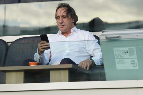 Mann sitzt auf der Fußballtribüne und schaut auf sein Handy