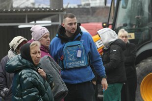 Menschen mit dicken Mänteln, Mützen und Decken in Arm