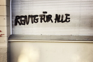 An einem Gebäude steht auf dem angegrauten Rolladen "RENTE FÜR ALLE"