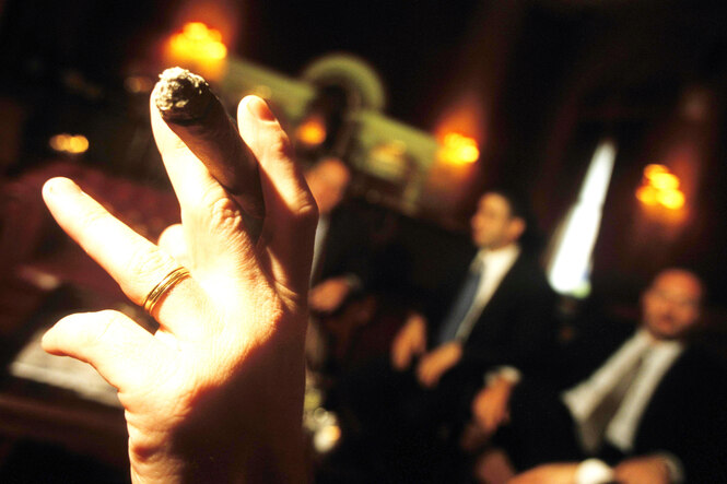 Eine Zigarre, im Hintergund mehrere Personen