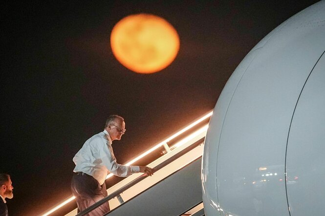 Kanzler Merz geht die gangway zu einem Flugzeug hoch.