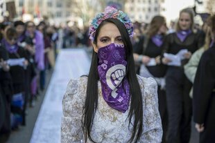 Eine vermummte Demonstrierende in einem weißen Brautkleid