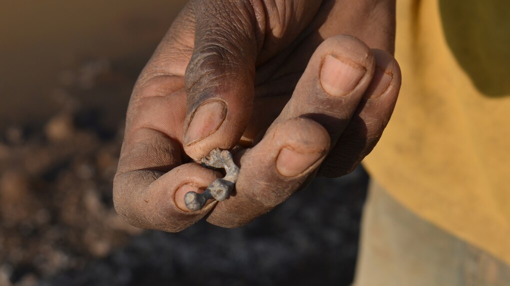 Eine Hand hält ein kleines Stück Blei
