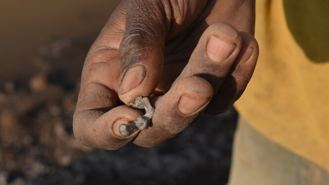 Eine Hand hält ein kleines Stück Blei