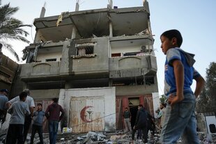 Ein Junge vor einem beschädigten Haus