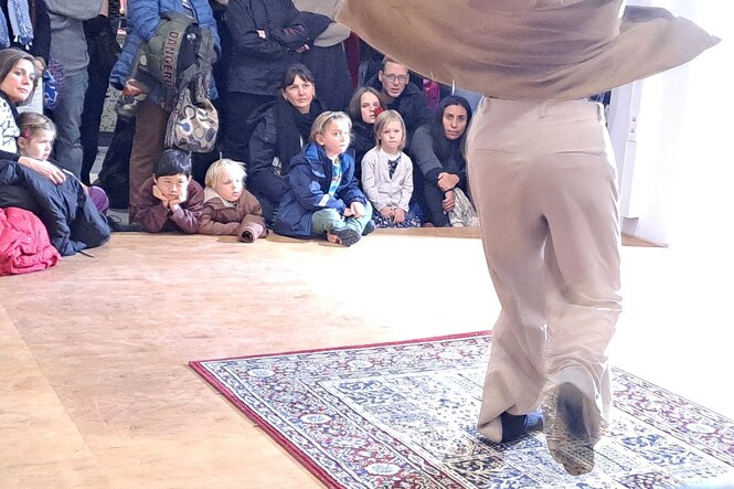 Kinder drängeln sich um die Bühne im Foyer, als die Tänzerin Eylo eine Kostprobe in Locking vorführt