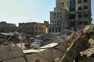 Ein Bagger zwischen beschädigten Gebäuden