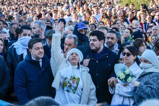 Eine Menschenmenge auf einer Kundgebung, im Vordergrund reckt die Mutter von Mehdi Kessaci die Hand in die Höhe