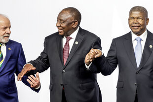 Die Politiker Lula, Ramaphosa und Lourenco halten sich bei einer Veranstaltung an den Händen.