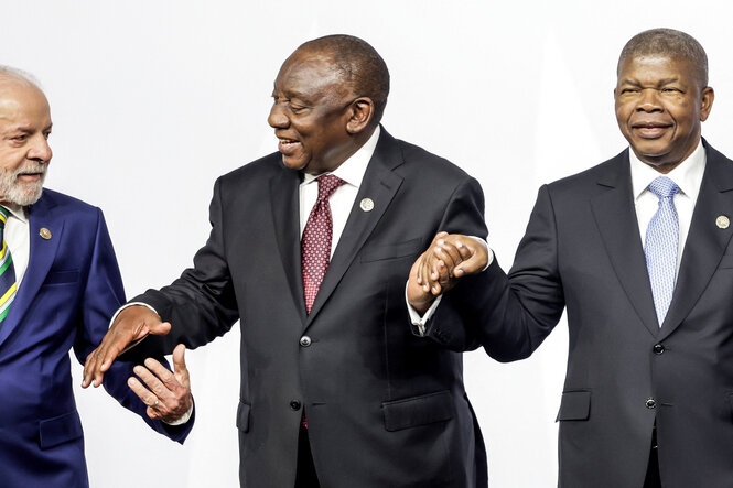 Die Politiker Lula, Ramaphosa und Lourenco halten sich bei einer Veranstaltung an den Händen.