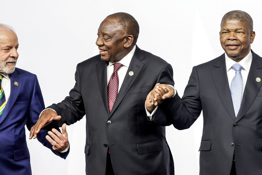 Die Politiker Lula, Ramaphosa und Lourenco halten sich bei einer Veranstaltung an den Händen.