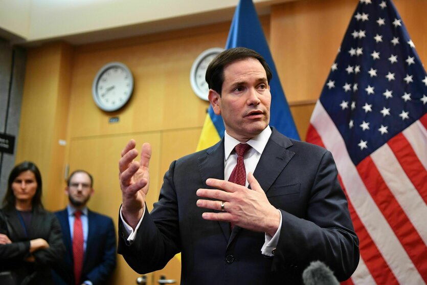 US-Außenminister Marco Rubio gestikulierend in einem Besprechungsraum, im Hintergrund eine amerikanische sowie eine ukrainische Flagge