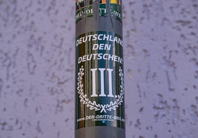 Ein Sticker der Neonazi-Partei "Der Dritte Weg" klebt an einem Schildermast