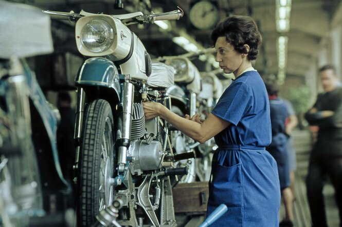 Eine Arbeiterin montiert Teile eines Motorrads im VEB Motorradwerk Zschopau der DDR.