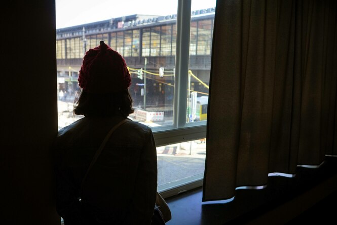 Ein Mensch mit Mütze schaut aus dem Fenster der C/O Galerie auf den Bahnhof Zoo