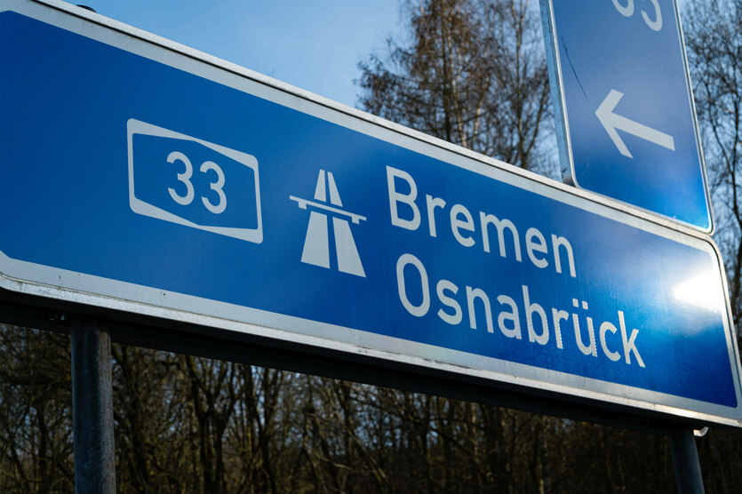 Auf einem Autobahnschild steht "33", ein Autobahnsymbol und "Bremen" und "Osnabrück". Darüber ist ein Schild mit einem Pfeil nach links