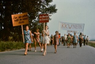 Sommerlich gekleidete Menschen recken Schilder in die Luft