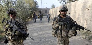 Soldatengruppe beim Einsatz in Afghanistan gehen an einer Mauer entlang
