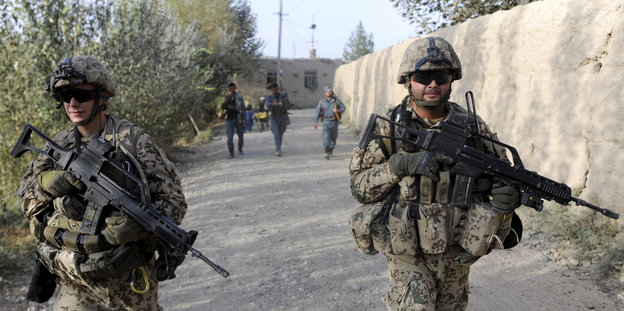 Soldatengruppe beim Einsatz in Afghanistan gehen an einer Mauer entlang