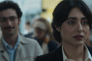 Die Schaupielerin Golshifteh Farahani im Vordergrund, roter Lippenstift, dunkle Haare, bei der Einreise am Flugahfen. Dahinter Darsteller Marandi, Jackett, Brille