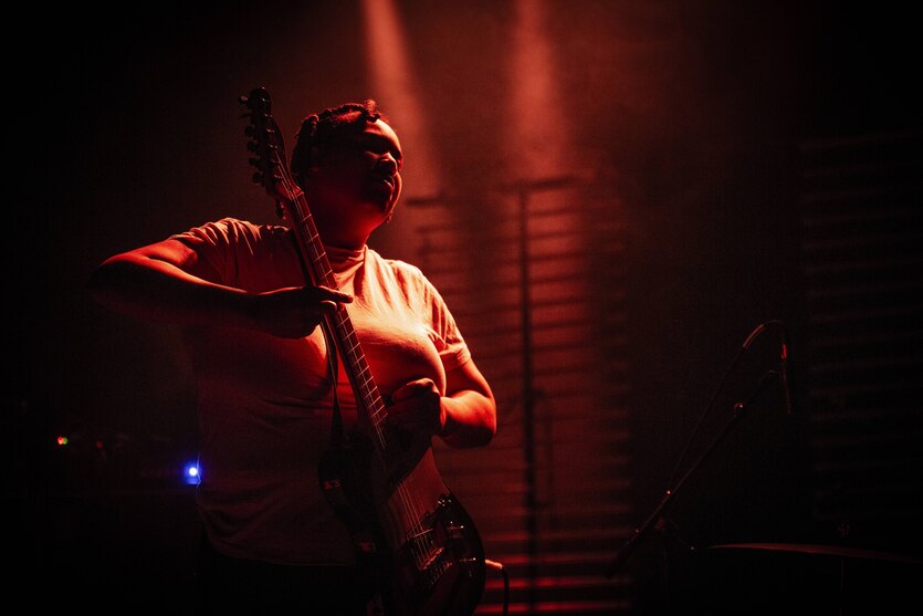 Eine Musikerin der Band Divide & Dissolve mit einer Elektrogitarre im Bühnenlicht