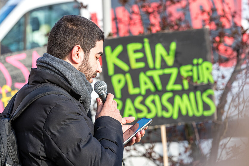 Bachir Alali vom Verein Opferperspektive spricht bei einer Demonstration vor dem Transparent "Kein Platz für Rassismus"