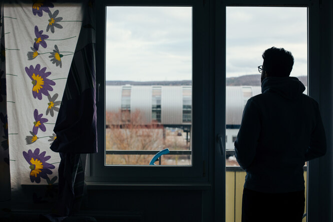 Der Schatten einer Person im Gegenlicht an einem Fenster.