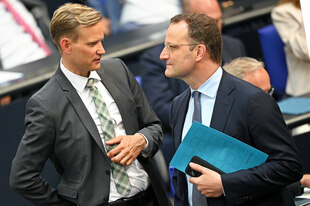 Jens Spahn (CDU, r), Vorsitzender der Unions-Fraktion im Bundestag, und Hendrik Streeck (CDU), Drogenbeauftragter der Bundesregierung, unterhalten sich im Plenum des Bundestags.