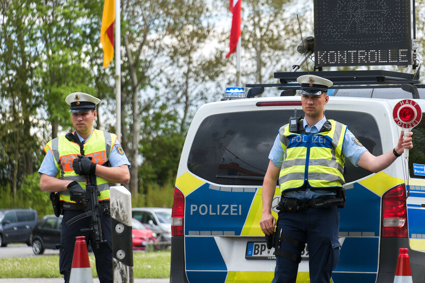 Bundespolizisten vor ihrem Fahrzeug, auf dessen Dach ein Display mit dem Wort "Kontrolle" aufleuchtet