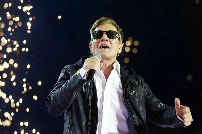 Ein Mann mit Sonnenbrille singt in ein Mikrofon