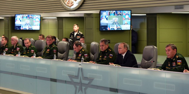 Wladimir Putin sitzt in einer Reihe mit Militärangestellten
