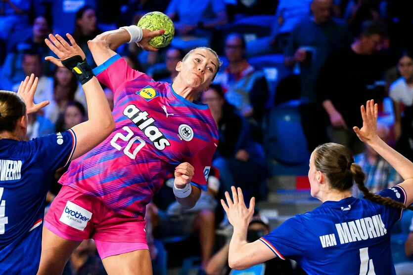 Emily Vogel beim Wurf, zwei Gegenspielerinnen versuchen den Ball mit ausgestreckten Händen abzuwehren