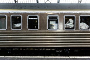 Ein stehender Schlafwagen, durch die Fenster ist Bettzeug zu sehen