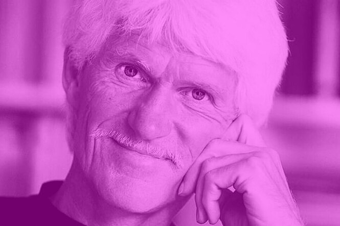 Porträt von Michael Hartmann: Sein Kopf stützt auf der rechten Hand, den Oberlippenbart säumen weiße Haare, so auch den Kopf. Der Blick wirkt zugewandt und aufmerksam.