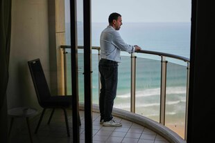 Porträt von Eli Sharabi auf einem Balkon mit Block auf das Meer.