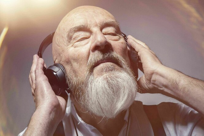 Ein Senior hört mit Kofphörern Musik